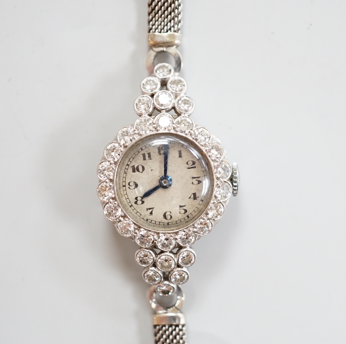 A lady's white metal and diamond set Movado manual wind cocktail watch, on a diamond set 9ct white metal mesh link bracelet, gross weight 18 grams.